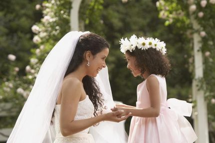 Hispanic bride and young girl smiling at each other